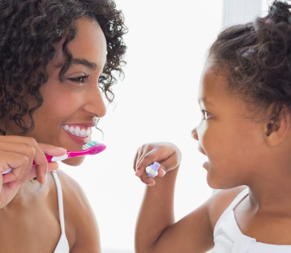 A parent helping her child brush her teeth
